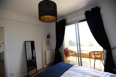 a bedroom with a bed and a sliding glass door at T2 Terrasse Vue Mer - Route des Sanguinaires in Ajaccio