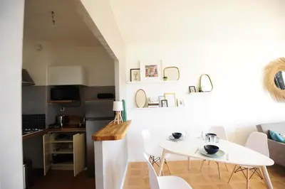 a kitchen and dining room with a white table and chairs at T2 Terrasse Vue Mer - Route des Sanguinaires in Ajaccio