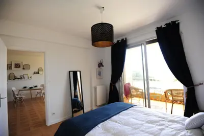 a bedroom with a bed and a large glass door at T2 Terrasse Vue Mer - Route des Sanguinaires in Ajaccio