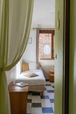 a small bedroom with a bed and a window at Hôtel Restaurant Sole e Monte in Cuttoli-Corticchiato