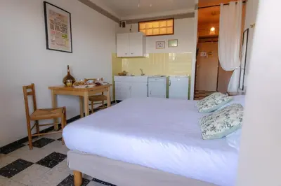 a bedroom with a bed and a table and a kitchen at Hôtel Restaurant Sole e Monte in Cuttoli-Corticchiato