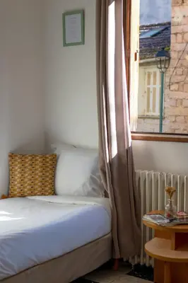 a bed sitting next to a window with a curtain at Hôtel Restaurant Sole e Monte in Cuttoli-Corticchiato