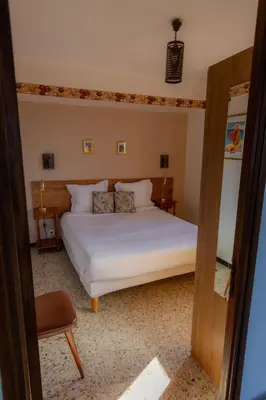a bedroom with a white bed and a chair at Hôtel Restaurant Sole e Monte in Cuttoli-Corticchiato