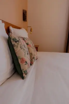 a white bed with two pillows on top of it at Hôtel Restaurant Sole e Monte in Cuttoli-Corticchiato