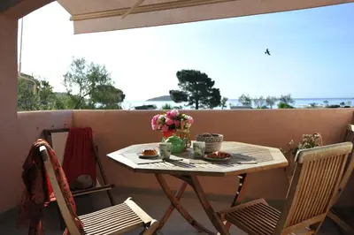 a table on a balcony with flowers on it at Cala di Sole Lecci in Porto-Vecchio