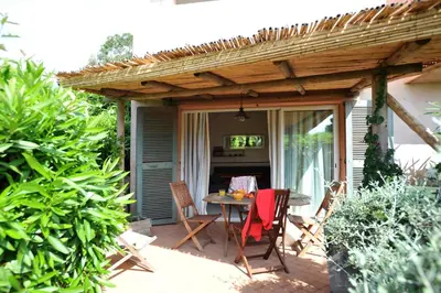a patio with a table and chairs under a pergola at Cala di Sole Lecci in Porto-Vecchio
