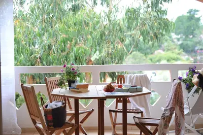 a table and chairs on a balcony with a window at Cala di Sole Lecci in Porto-Vecchio