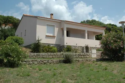a white house with a stone wall at Residence Capicciolo in Olmeto