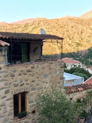 a stone building with a mountain in the background at Chez Marco Gîte & SPA CAPPELLINA in Muro