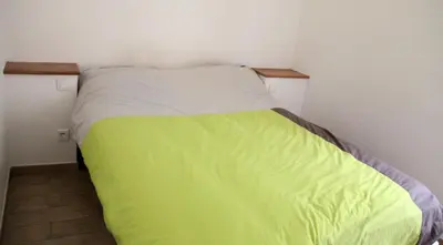 a small bedroom with a green and white bed at Charmant F2 dans joli village Corse in Omessa