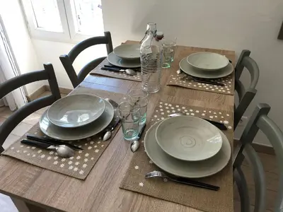 a wooden table with plates and glasses on it at Charmant F2 dans joli village Corse in Omessa