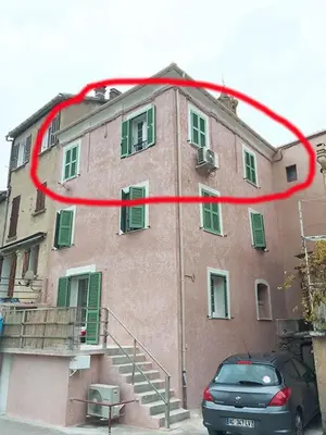 a building with a red circle on the side of it at Charmant F2 dans joli village Corse in Omessa