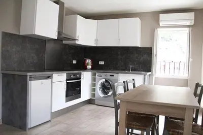 a kitchen with white cabinets and a table and a table and a sink at Charmant F2 dans joli village Corse in Omessa