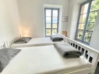 two beds in a room with two windows at Gîte du Chalet Pietri in Olivese