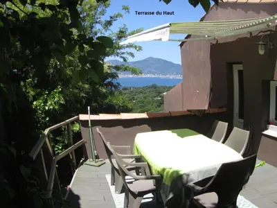 a table and chairs on a porch with a view of the water at Villa La Viva Porticcio in Porticcio
