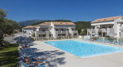 a swimming pool with people sitting in chairs next to a building at Résidence Odalys Casa d'Orinaju in Oletta