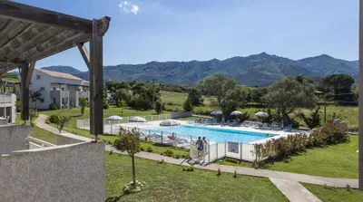 a villa with a pool and mountains in the background at Résidence Odalys Casa d'Orinaju in Oletta
