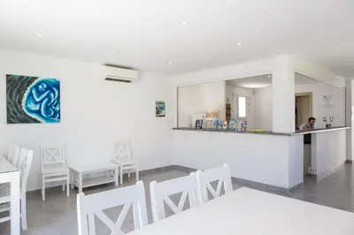 a dining room with white tables and chairs and a mirror at Résidence Odalys Casa d'Orinaju in Oletta