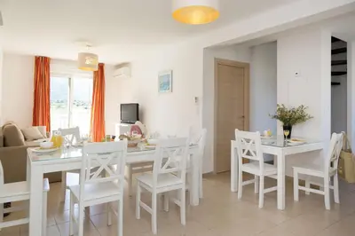 a kitchen and dining room with a white table and chairs at Résidence Odalys Casa d'Orinaju in Oletta
