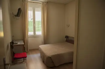 a small bedroom with a bed and a window at Hotel du Palais in Ajaccio
