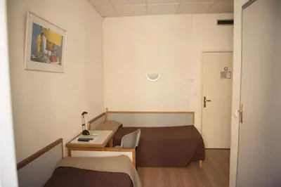 a small hotel room with two beds and a desk at Hotel du Palais in Ajaccio