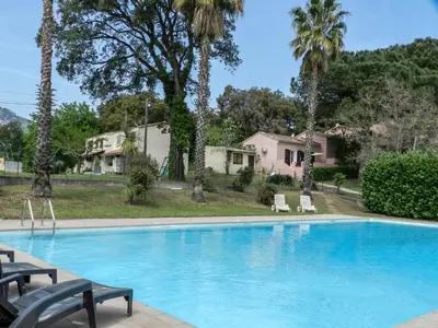 a swimming pool with chairs and palm trees at Holiday Home Cavoni by Interhome in Moriani Plage