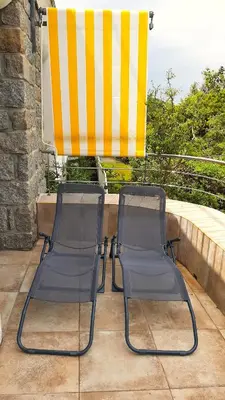two chairs and an umbrella on a balcony at Camélia Plein Soleil Bord de Plage in Coti-Chiavari