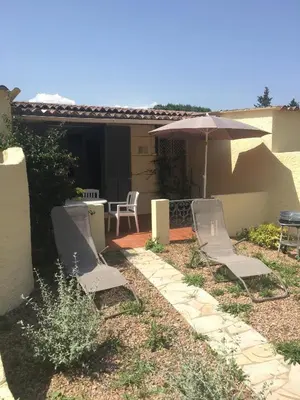 a yard with chairs and umbrellas in the grass at Bungalows Filippi in Porto-Vecchio