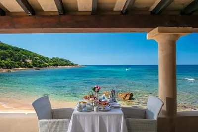 a table on the beach with a meal on it at Hotel Le Maquis in Porticcio