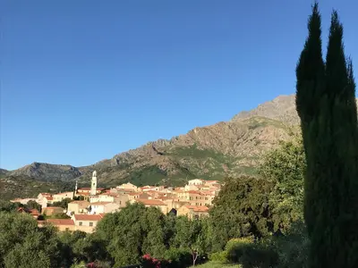 a town on a hill with a mountain in the background at Au pied des oliviers in Calenzana