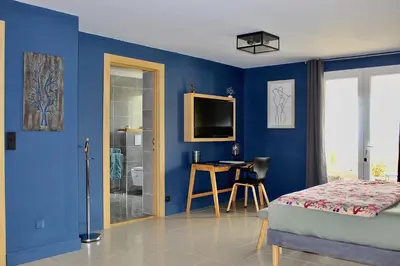 a bedroom with blue walls and a bed and a desk at Au pied des oliviers in Calenzana