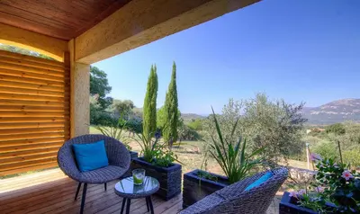 a porch with two chairs and a table and plants at Au pied des oliviers in Calenzana