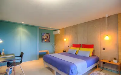a bedroom with a large bed with colorful pillows at Au pied des oliviers in Calenzana