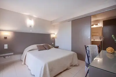 a bedroom with a white bed in a room at Hôtel Les Lentisques in Cargèse