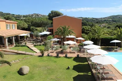 a resort with a pool and tables and umbrellas at Hôtel Les Lentisques in Cargèse