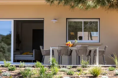 a patio with a table and chairs in front of a house at Hôtel Les Lentisques in Cargèse