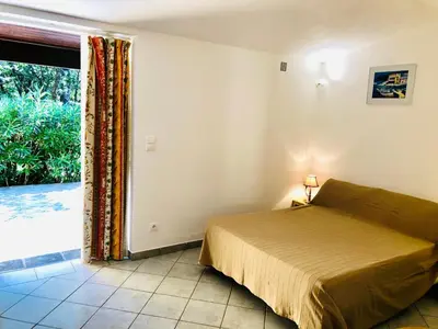 a bedroom with a bed and a large window at Résidence Les Lièges de Palombaggia in Porto-Vecchio