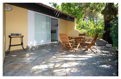 a patio with a table and chairs next to a house at Résidence Les Lièges de Palombaggia in Porto-Vecchio