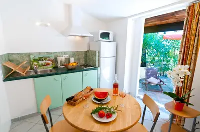 a kitchen with a wooden table with food on it at Résidence Les Lièges de Palombaggia in Porto-Vecchio