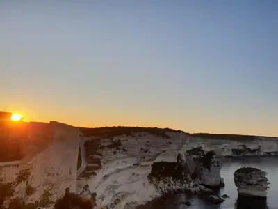 a sunset over a cliff with a body of water at chez dume in Bonifacio