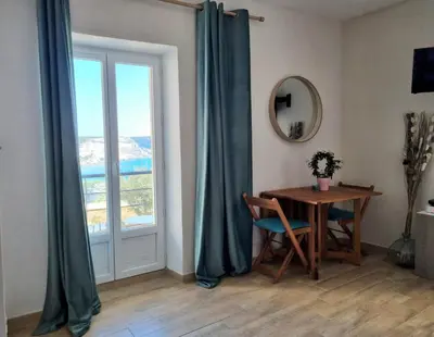 a dining room with a table and a window at chez dume in Bonifacio