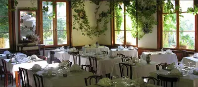 a room with tables and chairs with white tables and windows at Hotel Monte d'Oro in Vizzavona