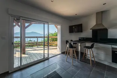 a kitchen with a counter and stools in front of a balcony at T2 vue sur le golfe d'Ajaccio in Porticcio