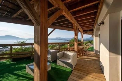 a wooden deck with chairs and a table and the ocean at T2 vue sur le golfe d'Ajaccio in Porticcio