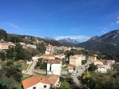 a town on a hill with mountains in the background at Petite maison proche de la nature in Vico