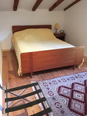a bedroom with a bed and a chair and a rug at Petite maison proche de la nature in Vico