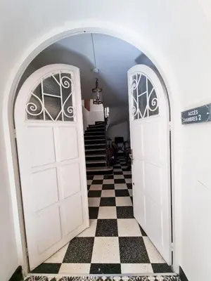 an archway with two white doors and a checkered floor at Hôtel Villa Les Orangers in Olmeto