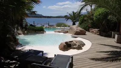 a wooden boardwalk with umbrellas on a lake at Maranatha, front de mer avec plage in Porto-Vecchio