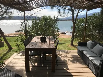 a sliding glass door leading to a patio with a table at Maranatha, front de mer avec plage in Porto-Vecchio