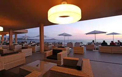 a restaurant with a view of the ocean with chairs and umbrellas at Radisson Blu Resort & Spa, Ajaccio Bay in Porticcio